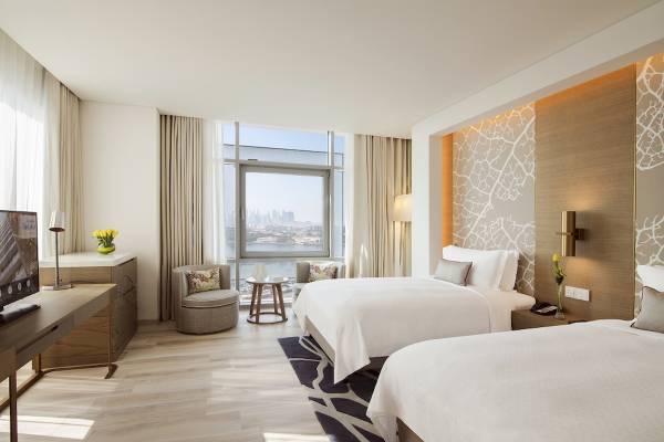 Zweibettzimmer im Al Bandar Rotana Hotel mit Stadtblick, modernen Möbeln und Dekor.