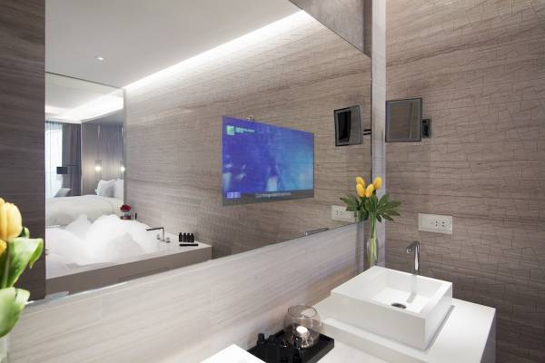 Badezimmer im Al Bandar Rotana Hotel mit Spiegel, Badewanne und Fernseher