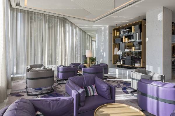 Lobby-Lounge-Bereich des Al Bandar Rotana Hotels mit violetten Sesseln und weißen Vorhängen.