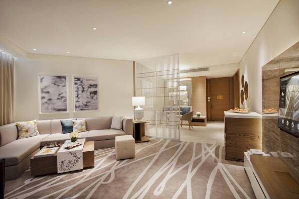 Wohnbereich im Al Bandar Rotana Hotel mit Sofa, Tisch und Fernseher