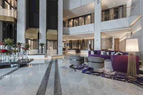 Lobby des Al Bandar Rotana Hotels mit Marmorboden, luxuriösen Möbeln und Blumenarrangements.