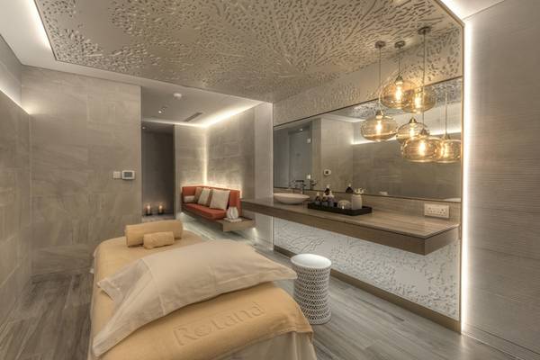 Massagebehandlungsraum im Al Bandar Rotana Hotel mit Liege, Couch, Waschbecken und Spiegel