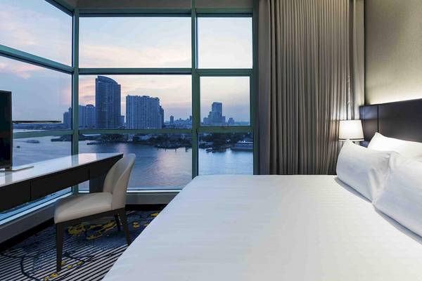 Zimmer im Chatrium Hotel Riverside Bangkok mit Blick auf die Skyline und den Fluss.
