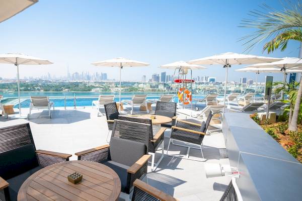 Dachterrasse des Al Bandar Rotana Hotels mit Sitzgelegenheiten, Sonnenschirmen und Blick auf die Stadt