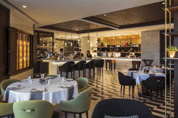 Innenbereich des Al Bandar Rotana Hotels mit Bar und Tischen.