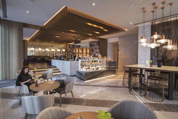 Loungebereich im Al Bandar Rotana Hotel mit Sitzgelegenheiten und einer Theke.