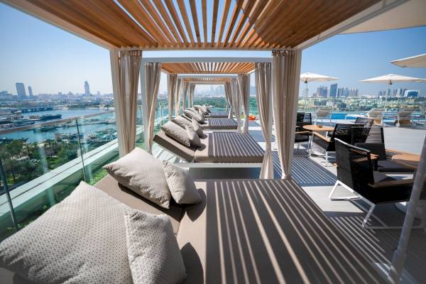 Al Bandar Rotana Dachterrasse mit Lounge-Bereich und Blick auf die Stadt.