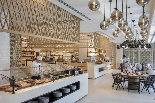 Innenansicht des Al Bandar Rotana Hotel Restaurants mit Buffet und gedeckten Tischen.