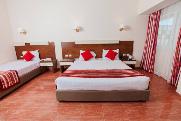 Doppelzimmer im Golden Beach Resort mit zwei Betten, roten Kopfkissen und braunen Kopfteilen.