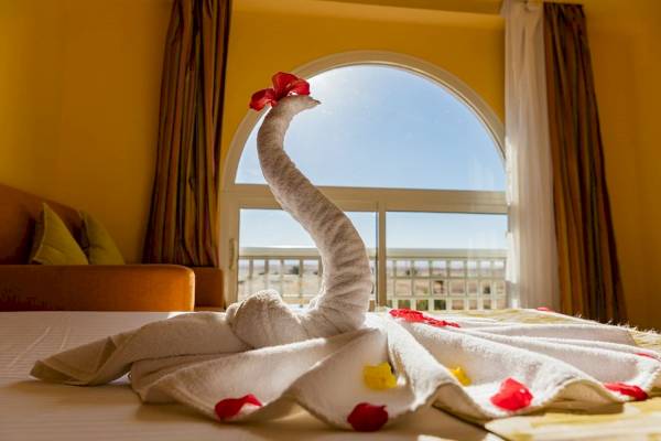 Schwan aus Badetüchern auf einem Bett im Zimmer des Golden Beach Resorts mit Fenster im Hintergrund.