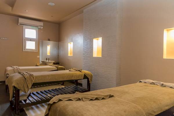 Behandlungszimmer im Golden Beach Resort mit drei Liegen und einer weißen Wand.