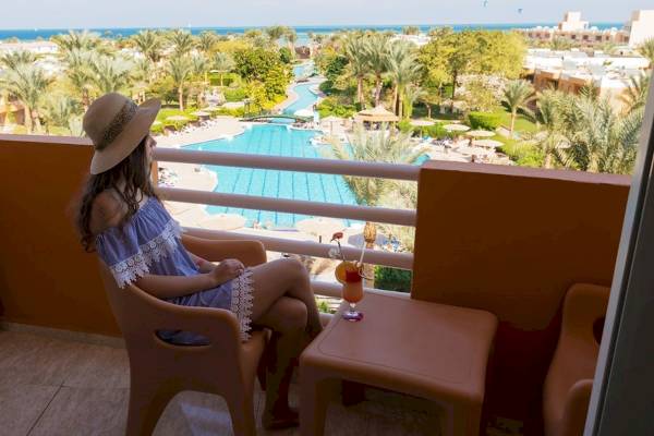Frau sitzt auf dem Balkon mit Blick auf den Pool im Golden Beach Resort.