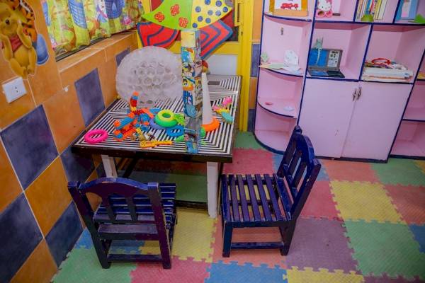 Ein Kinderzimmer mit bunten Wänden, Spieltischen und Spielzeug.