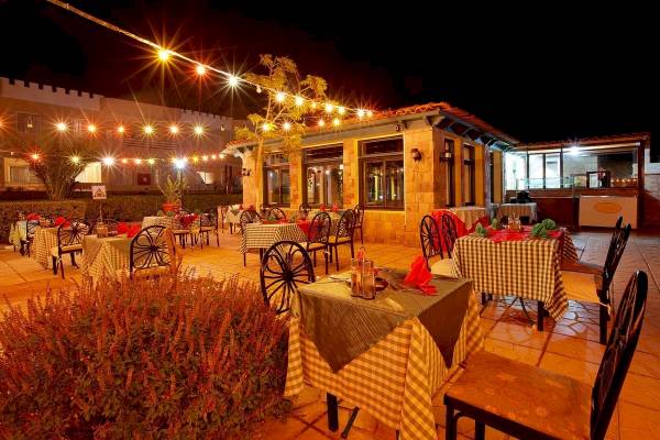 Nachtansicht der Terrasse des Golden Beach Resort mit illuminierten Tischen und Stühlen.