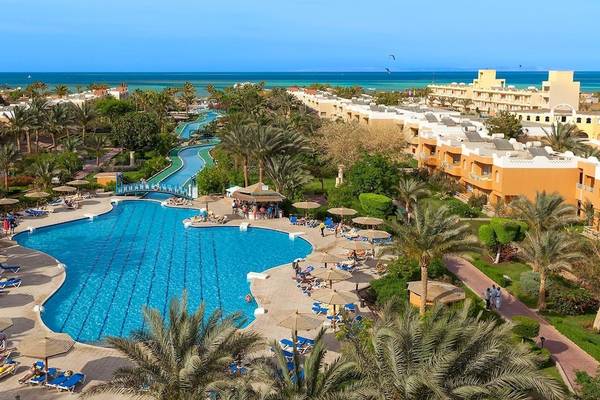 Luftaufnahme des Golden Beach Resorts mit großem Pool, Sonnenschirmen und Strand