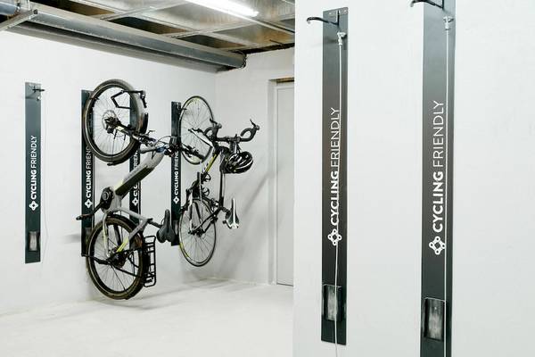 Fahrräder, die an der Wand eines Hotels aufgehängt sind, mit Schildern, die 'Cycling Friendly' und 'Cycling' bedeuten.