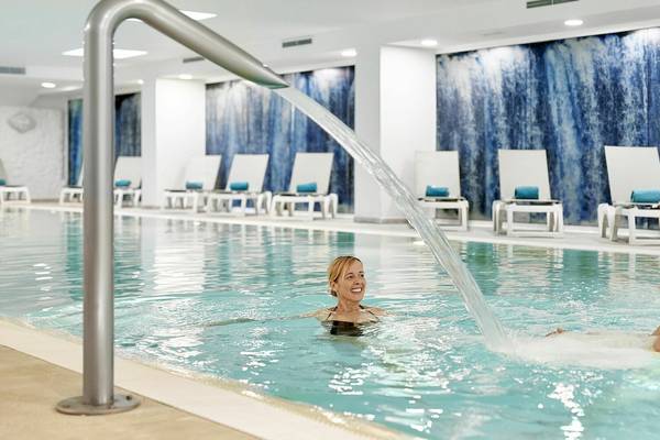 Ein Schwimmbad im Iberostar Cristina Hotel mit Wasserfall und zwei Personen, die darin schwimmen.