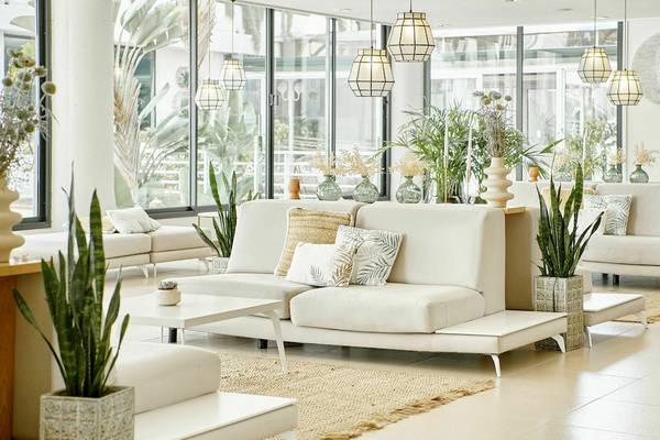 Lobby des Iberostar Cristina Hotels mit weißen Möbeln, Pflanzen und großen Fenstern.