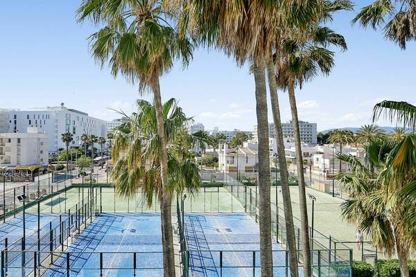 Aussicht auf Tennisplatz im Hotel Iberostar Cristina mit mehreren Palmen und Gebäuden im Hintergrund.