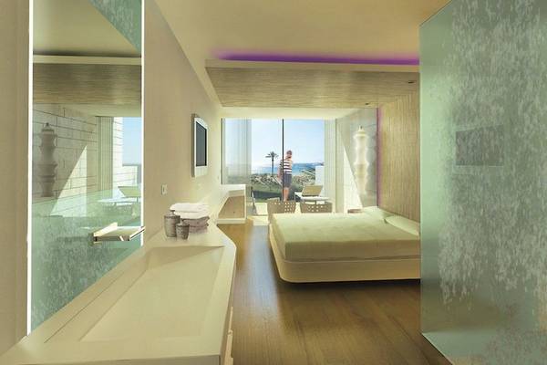 Innenansicht eines Zimmers im Hard Rock Hotel Ibiza mit Bett, Badezimmer und Meerblick.