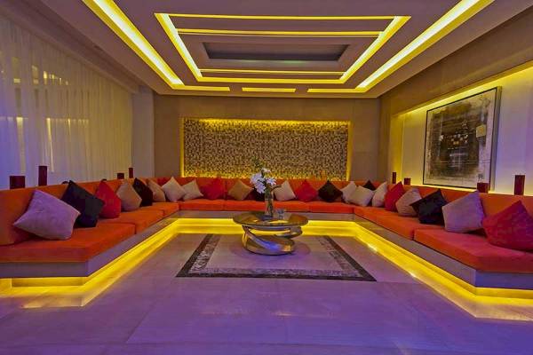 Loungebereich im Premier Le Reve Hotel mit orangefarbenen Sofas, Kissen und leuchtenden gelben Akzenten.