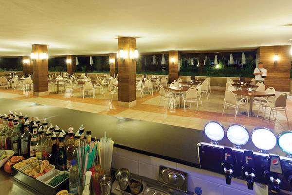 Innenbereich des Sherwood Dreams Resort Hotels mit vielen Tischen und Stühlen, serviertheke und einer Person