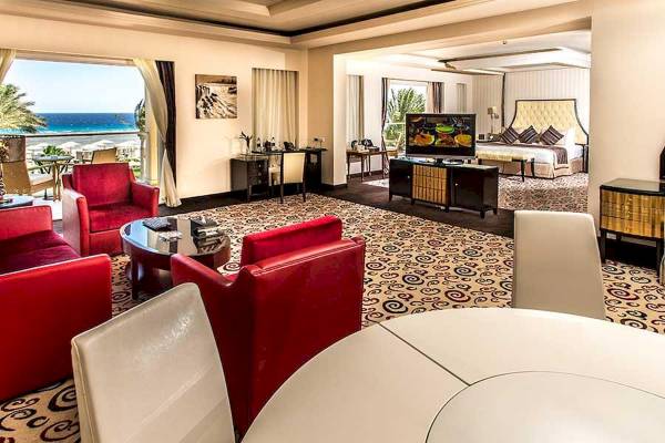 Innenansicht der Suite im Premier Le Reve Hotel mit Meerblick, roten Sesseln, Schreibtisch und Fernseher.
