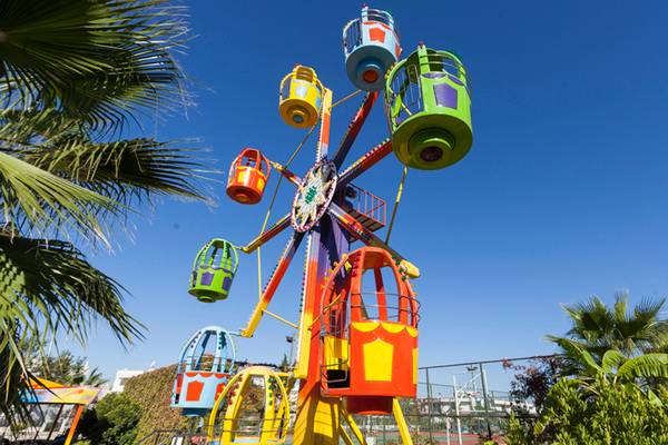 Bunt farbener Karussell im Freizeitpark mit vielen farbigen Gondeln unter blauem Himmel