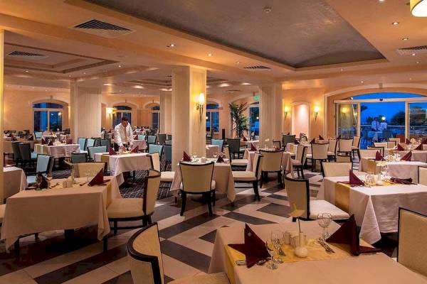 Innenansicht des Restaurants im Premier Le Reve Hotel & Spa mit gedeckten Tischen und einem servierenden Kellner.