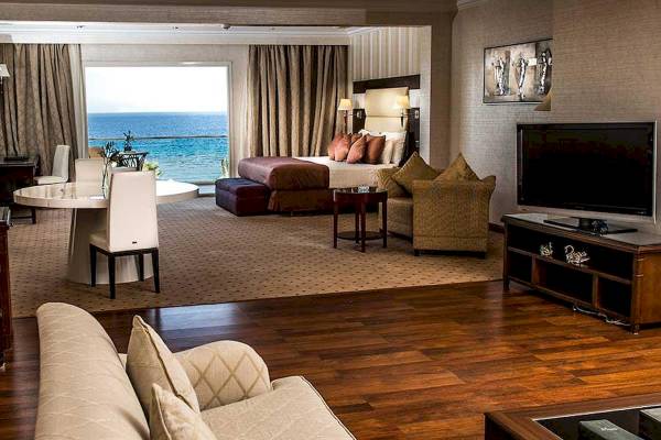 Suite mit Meerblick im Premier Le Reve Hotel & Spa mit großem Bett, Tisch, Fernseher und Aussicht auf den Ozean.