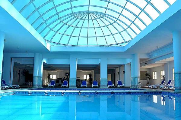 Innenpool des Premier Le Reve Hotel & Spa mit blauen Liegen und einer Glaskuppel