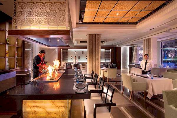 Grillbereich im Restaurant des Premier Le Reve Hotel & Spa mit einem Koch, der Speisen brät.