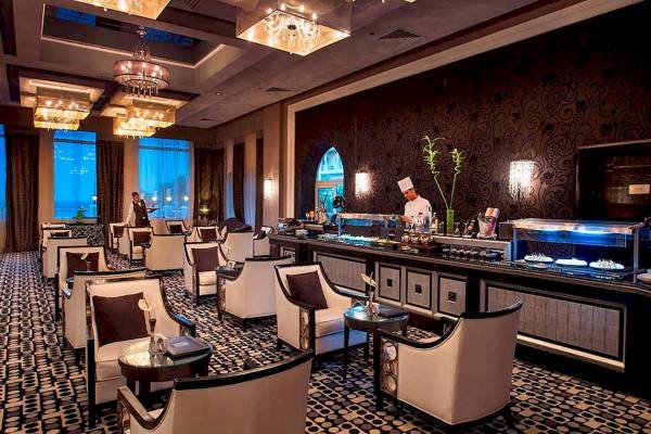 Das Premier Le Reve Hotel & Spa mit eleganter Lounge und Barbereich, wo ein Koch hinter der Theke steht.