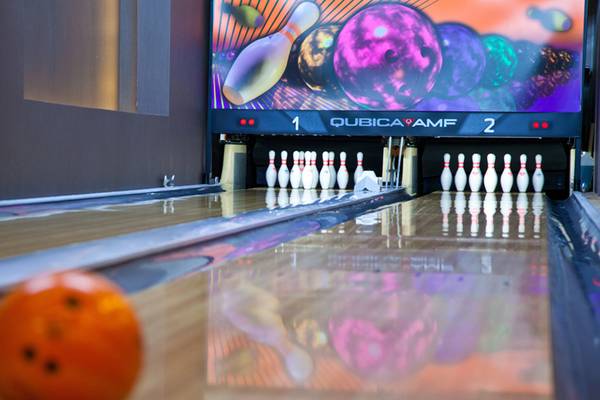 Bowlingbahn im Sherwood Dreams Resort mit Pins und Ball, Fernseher zeigt Spiel.