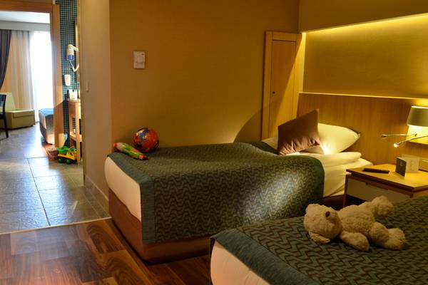 Kinderzimmer im Sherwood Dreams Resort mit zwei Betten, Spielzeug und einer offenen Tür.