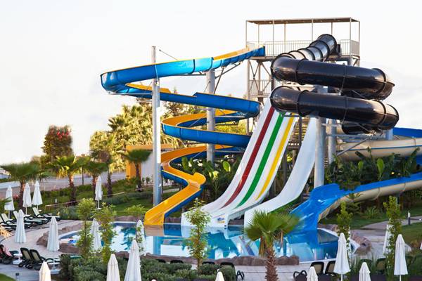 Mehrere Wasserrutschen im Sherwood Dreams Resort mit bunten Farben und umgeben von Palmen und Sonnenschirmen.