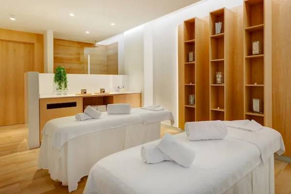 Wellness-Bereich im Hipotels Gran Playa de Palma mit zwei weißen Massagetischen und Holzschränken.
