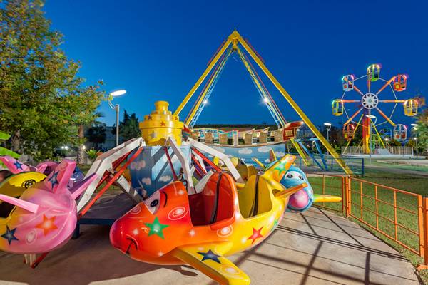 Farbige Flugzeugkarussells und ein Riesenrad im Sherwood Dreams Resort Spielplatz bei Abend