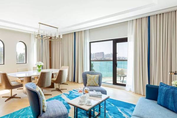 Wohnzimmer des Taj Exotica Resort & Spa The Palm Dubai mit Esstisch, Sofa und Meerblick.