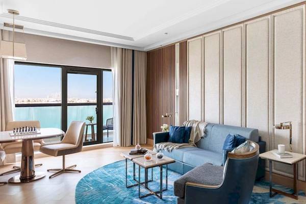 Wohnbereich im Taj Exotica Resort & Spa The Palm Dubai mit blauem Sofa, Esstisch und Seeblick.