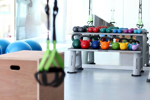 Fitnessstudio mit verschiedenen Gewichten und Trainingsgeräten auf einem Regal.