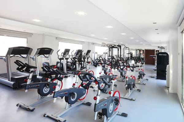 Fitnessraum im Iberostar Playa de Muro mit verschiedenen Trainingsgeräten wie Laufbändern und Spinrädern.