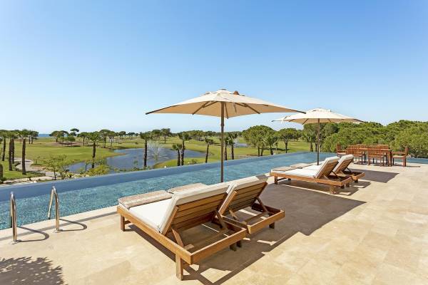 Pool-Terrasse mit Liegen und Umbrellas im Cullinan Belek Hotel mit Blick auf den Golfplatz