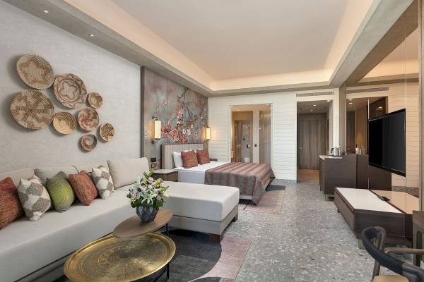 Innenansicht einer Suite im Cullinan Belek Hotel mit Sofa, Bett, Tisch und Fernseher.