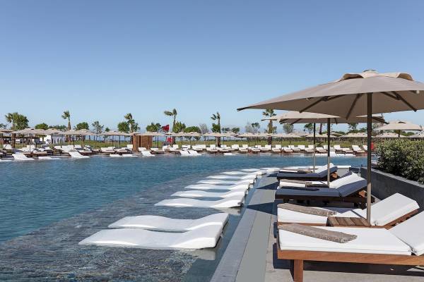 Poolbereich im Cullinan Belek Hotel mit weißen Liegestühlen und Sonnenschirmen.