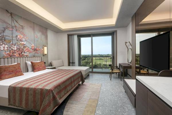 Innenansicht eines Zimmers im Cullinan Belek Hotel mit Bett, Sofa, Schreibtisch und Fernseher.