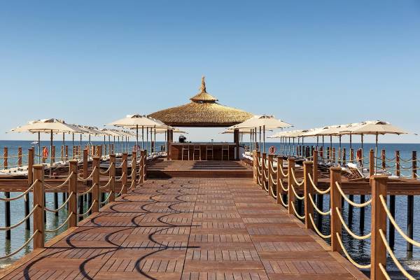Hotelterrasse am Wasser mit Sonnenschirmen und Liegen des Cullinan Belek