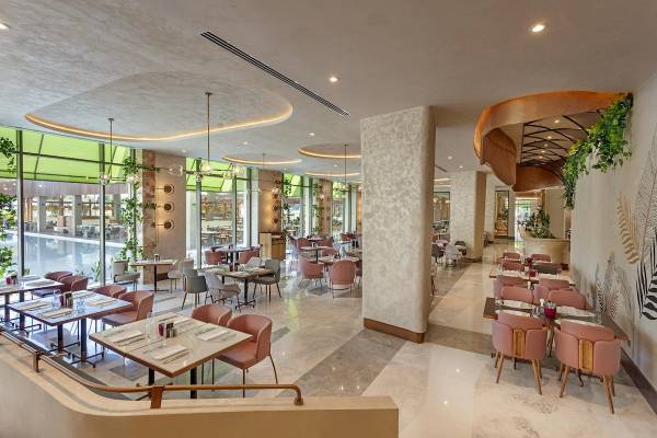 Innenansicht des Restaurants im Cullinan Belek Hotel mit runden Tischen und pinken Stühlen.