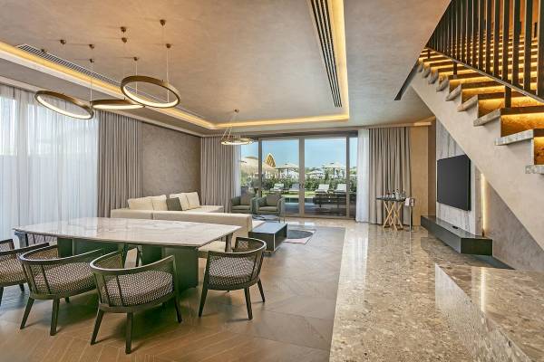 Wohnzimmer im Cullinan Belek Hotel mit Möbeln, Tisch, Sofa, Fernseher und gefliestem Boden.
