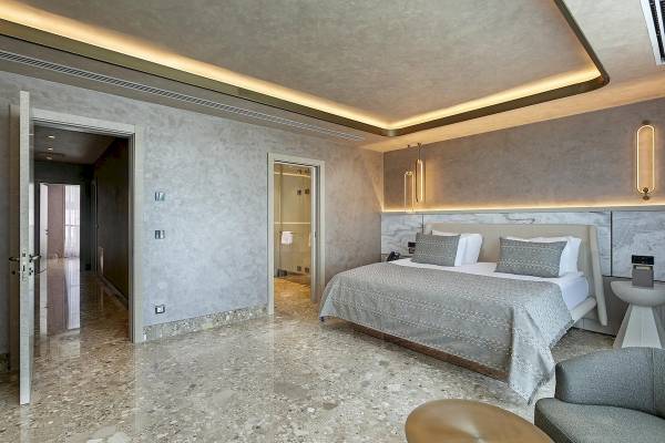 Schlafzimmer im Cullinan Belek Hotel mit einem Bett, Marmorboden und modernen Leuchten